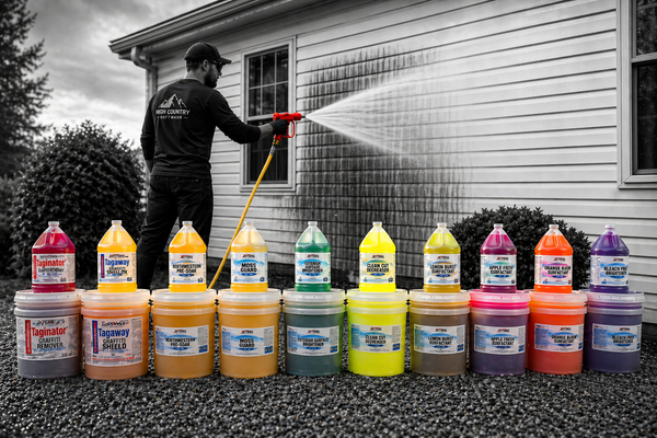 Man soft washing the side of a house with a row of soft washing and pressure washing chemicals in front. 