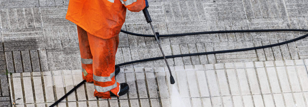 Worker cleaning a street sidewalk with pressurized water. Copy space