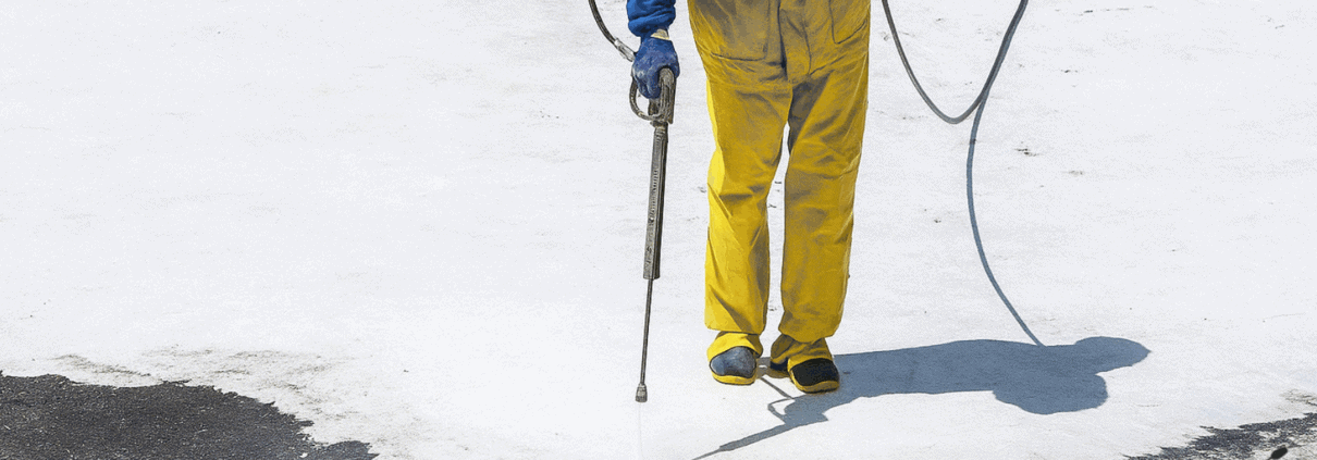 man wearing winter safety equipment pressure washing in the snow
