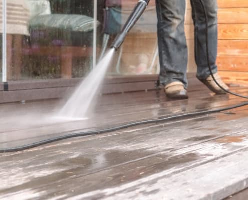 Man Pressure Washing a Deck